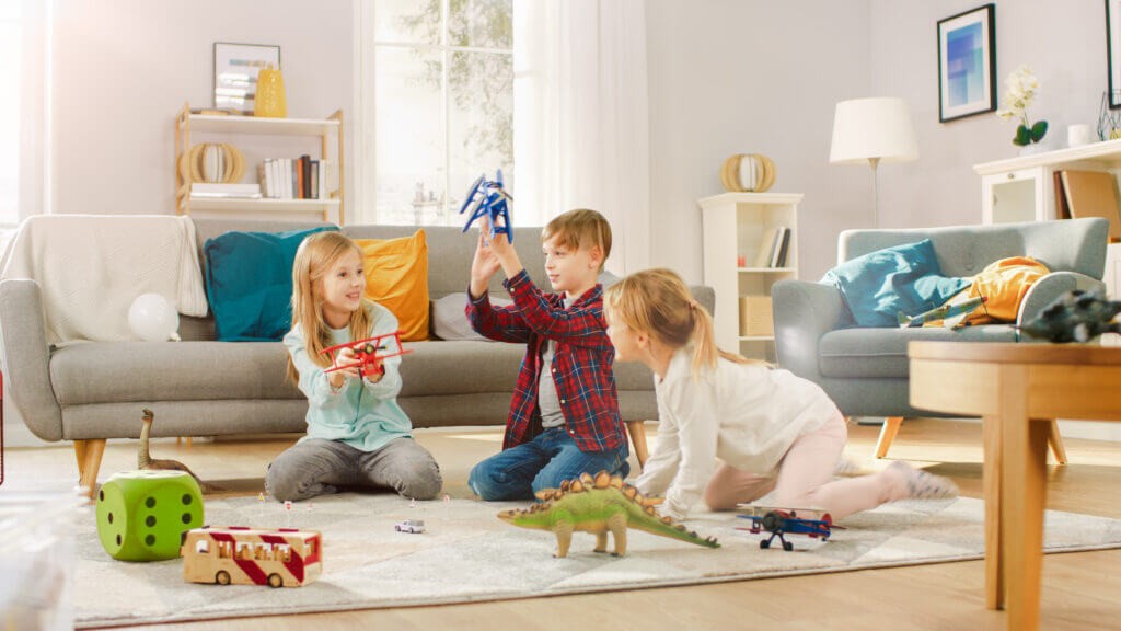 Three kids playing with toys in living room