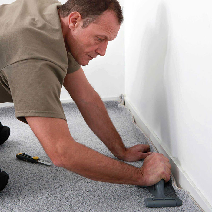 Man installing grey carpet | Off-Price Carpet Outlet